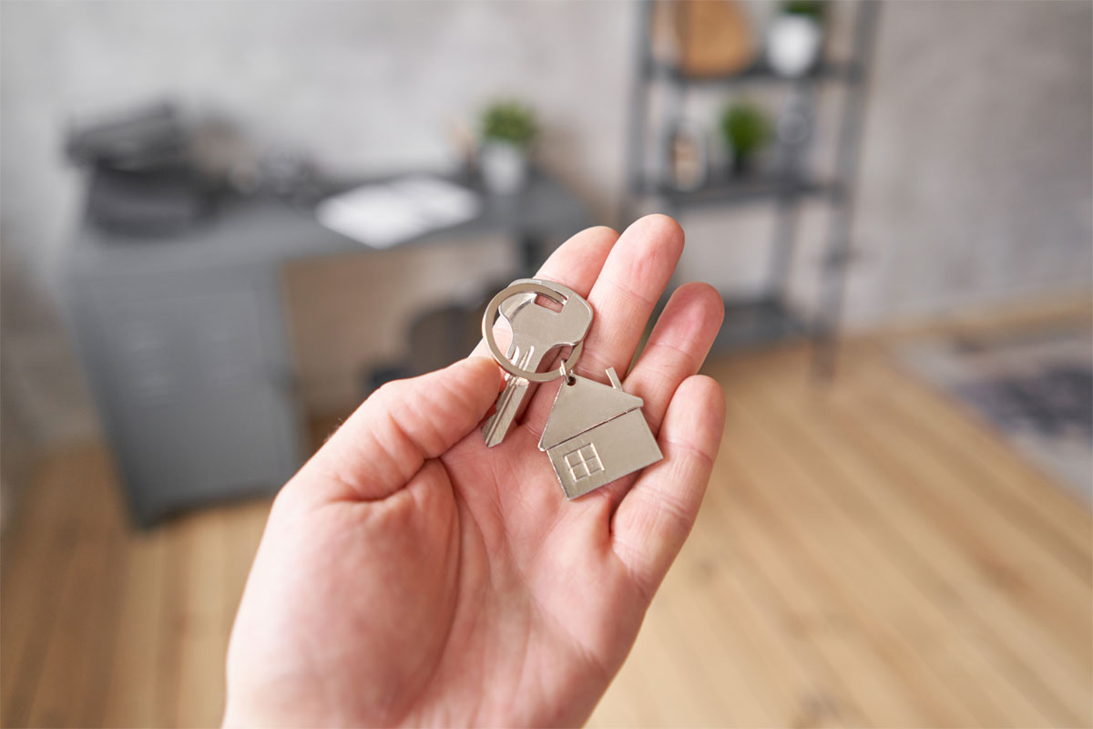 Single silver house key with keyring in left palm at home office